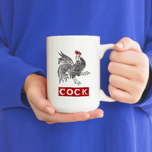 A photo of a fun coffee mug. It has a black strutting cockerel on it. Text below graphic reads COCK in red.
