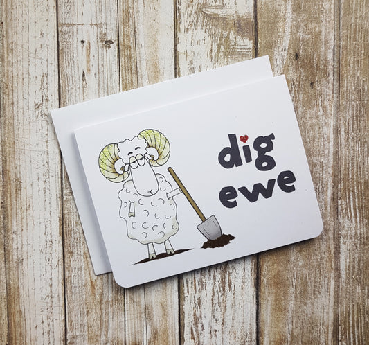 A photo of a white valentines card. It has a cartoon sheep on it with a shovel. Text reads, 'Dig Ewe.'