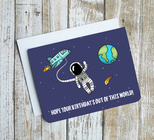 A photo of a dark blue birthday card. It has a cartoon astronaut on it with a cartoon earth behind. Text on card reads, 'Hope Your Birthday's Out of This World!'