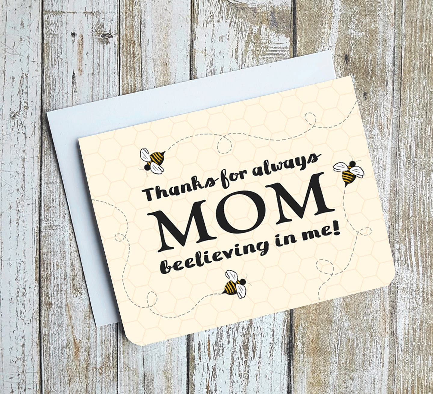 A photo of a mothers day card. It has bees buzzing around on it. Text reads, Thanks for always beelieving in me, Mom.