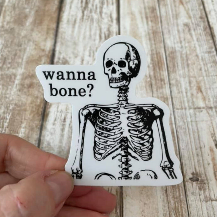 Vinyl Sticker featuring a skeleton (waist up) with text "Wanna Bone?" in black and white.