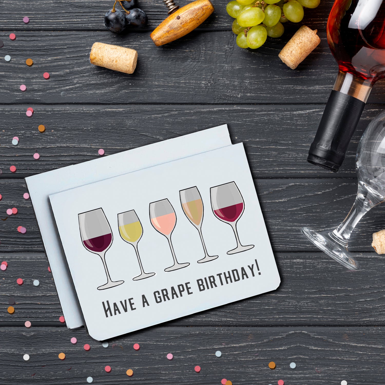 A photo of a white birthday card. It has 5 illustrated wine glasses on it in varying size with varying amounts of red, white, and rose wine in each. Text below says, 'Have a Grape Birthday!'