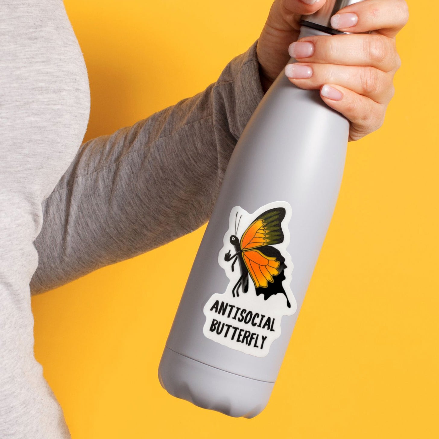 A photo of a vinyl sticker of cartoon monarch butterfly with its finger up. Text on cheeky sticker reads 'Antisocial Butterfly.' The sticker is stuck to a white reusable water bottle.