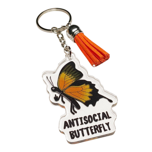 A photo of a vinyl keychain. It has a monarch butterfly on it giving the middle finger. Text on keychain reads, Antisocial Butterfly.
