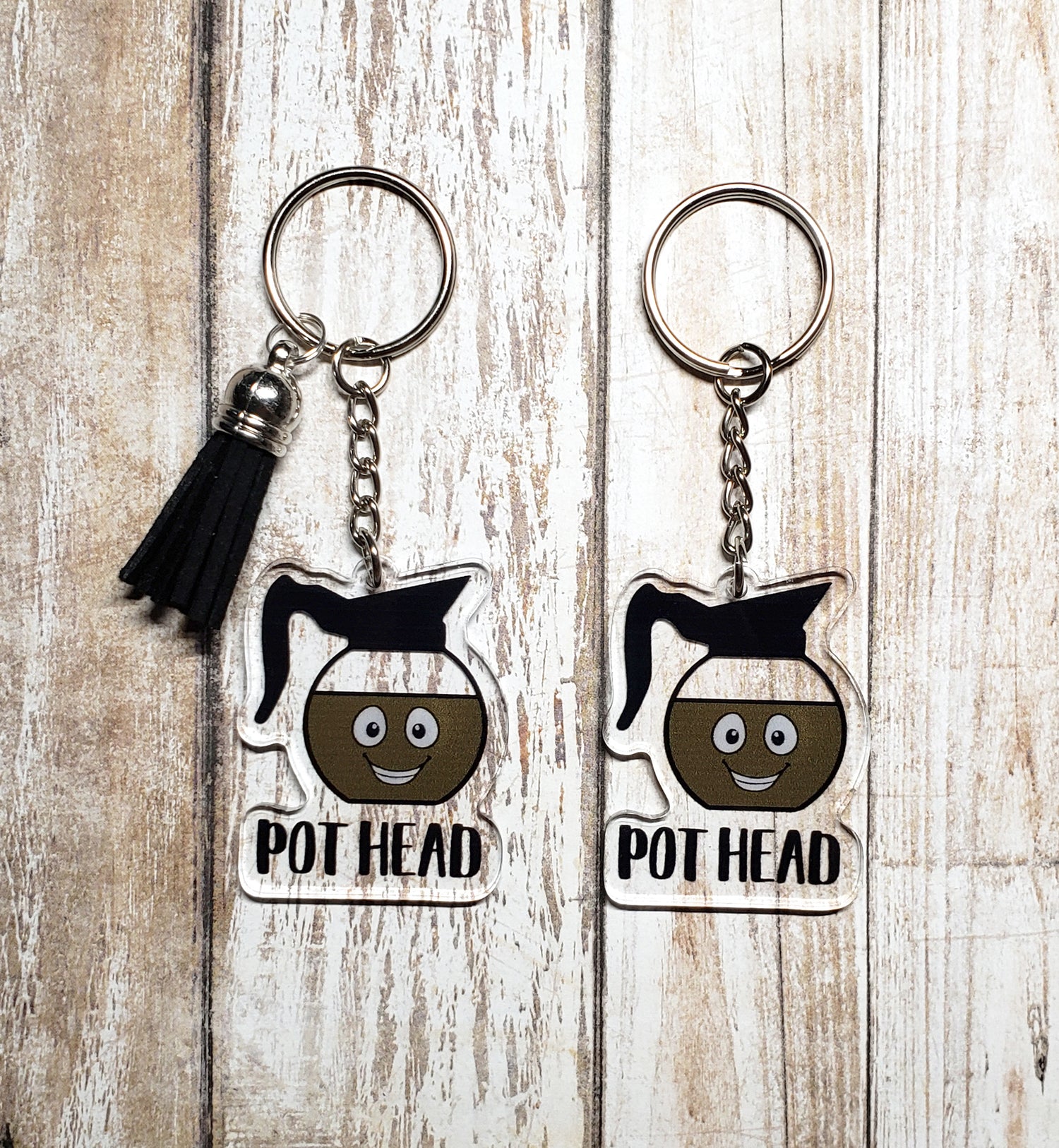 A photo of two acrylic keychains. The keychains have a smiling coffee pot on them. Text on key chain reads 'Pot Head.'