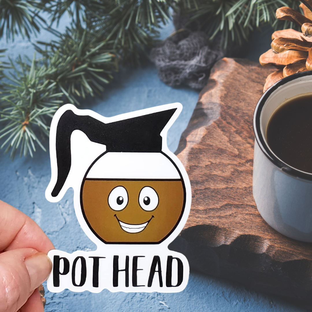 A photo of a sticker. The sticker has an illustrated, smiling coffee pot on it. Text on sticker reads 'Pot Head.''