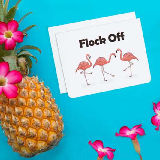 A photo of a greeting card. It has three flamingos on it. Text above reads, Flock Off.