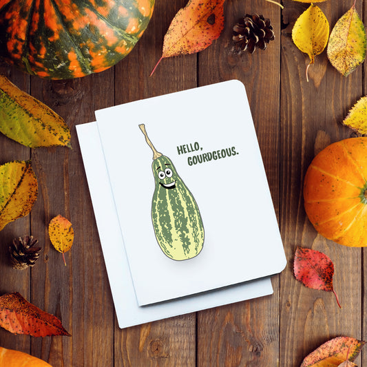 A photo of a white fun card. It has a smiling cartoon gourd on it. Text reads, 'Hello, Gorgeous.'