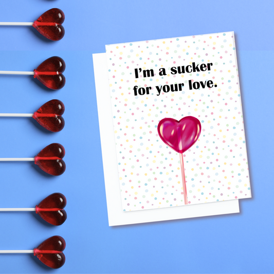 Valentines card. It has a heart shaped lollypop on it. Text reads, I'm a sucker for your love.