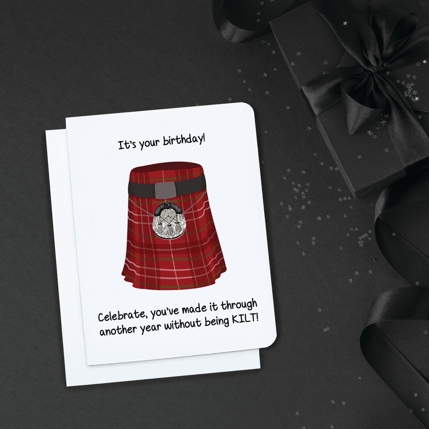A photo of a white birthday card. It has a cartoon kilt on it. Text on card reads, 'It's Your Birthday! Celebrate, you've made it through another year without being kilt!'