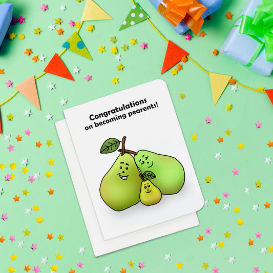A photo of a baby shower card. It has a two big cartoon pears, and one little pear huddled together. Text one card reads, 'Congratulations on becoming pearents!'