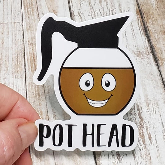 A photo of a sticker. The sticker has an illustrated, smiling coffee pot on it. Text on sticker reads 'Pot Head.''