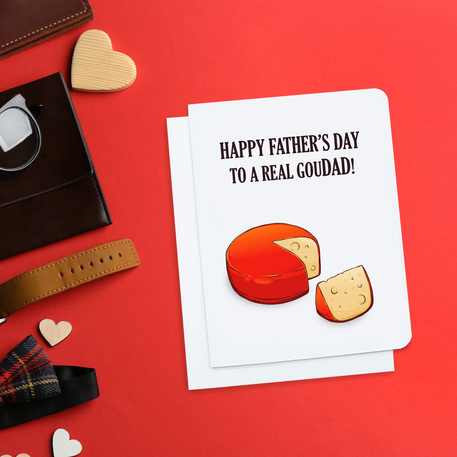 A photo of a fathers day card. It has a big red cheese on it with a slice missing. Text reads, Happy Father's Day to a real gouDAD!