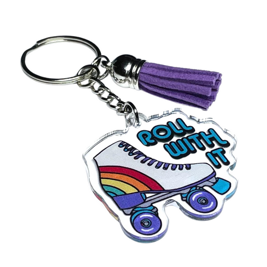 A photo of a cute keychain. It has a retro roller-skate on it. Text reads, Roll With It.