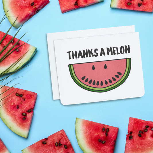 A photo of a white thank you card. It has a slice of cartoon watermelon on it. Its pips make a smiley face. Text on card reads, 'Thanks a Melon.'