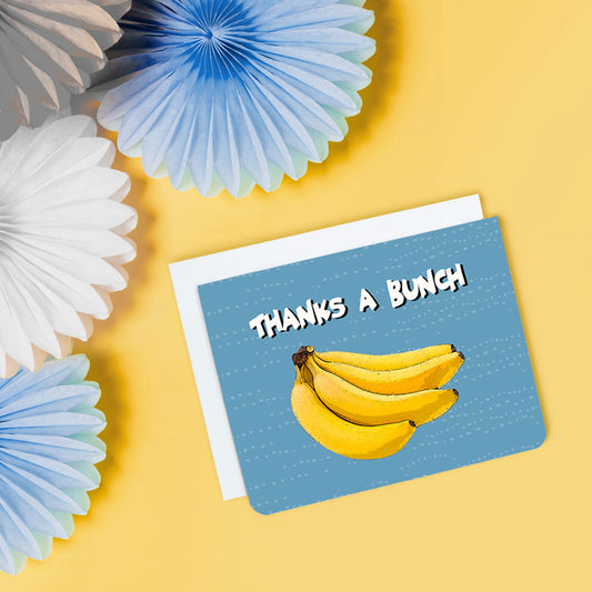 A photo of a blue thank you card. It has a bunch of cartoon bananas on it. Text on card reads, 'Thanks a Bunch.'