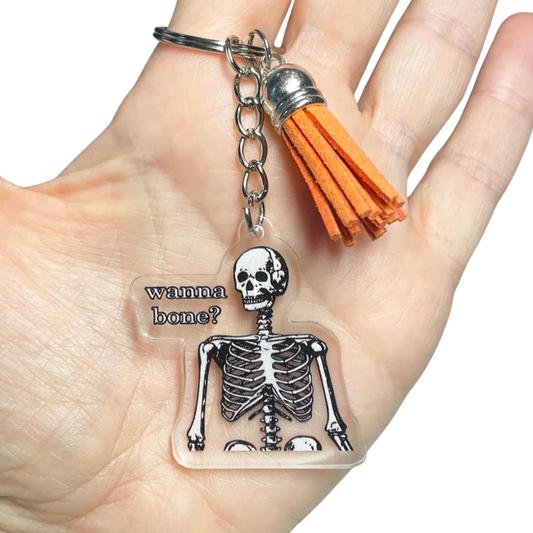A photo of a funny keychain. It has a skeleton on it. Text reads, Wanna Bone?