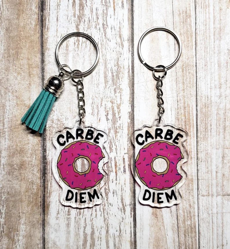 A photo of two key chains. They're bitten pink donuts. Text on keychain reads Carbe Diem.