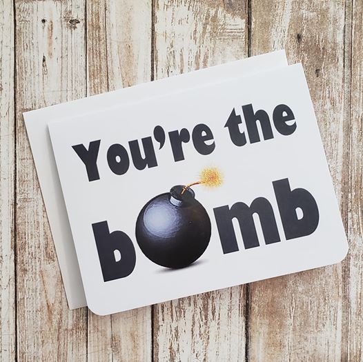A white greeting card. It says 'You're The Bomb' on it. The 'O' in the word 'Bomb' is a bomb.