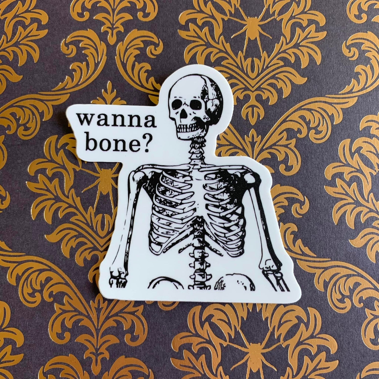 A photo of a skeleton sticker. Text reads 'Wanna Bone?'