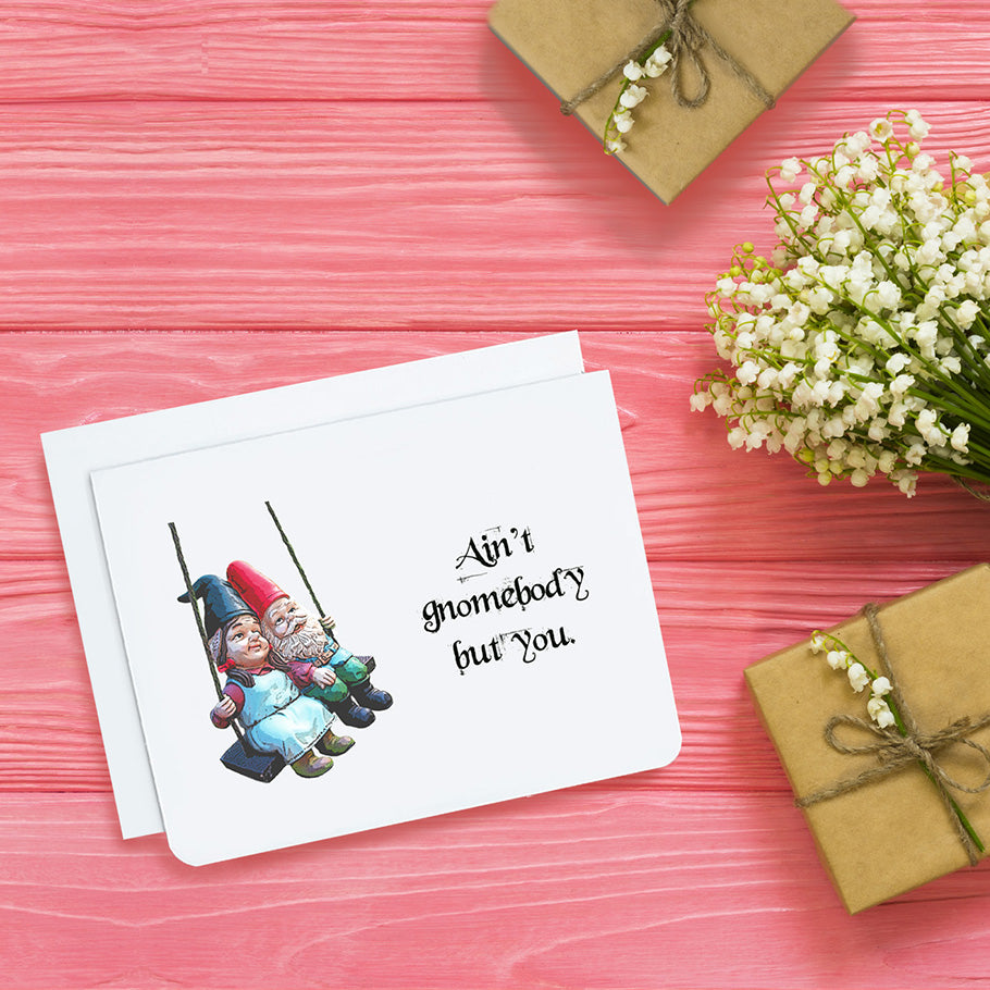 A photo of a cute greeting card. It has two elderly gnomes on a swing. Text on card reads, 'Ain't gnomebody but you.' 