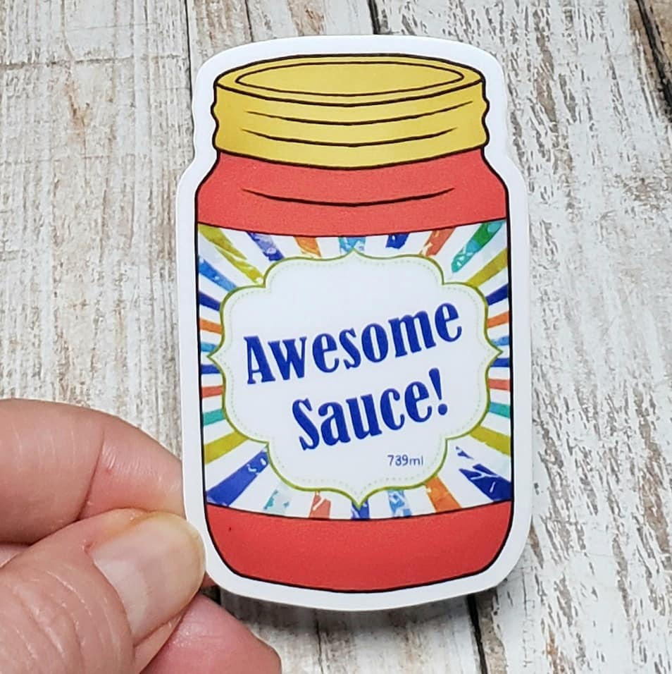 A photo of a vinyl sticker. The sticker is of an illustrated jar of sauce. Text on sauce label reads 'Awesome Sauce!'