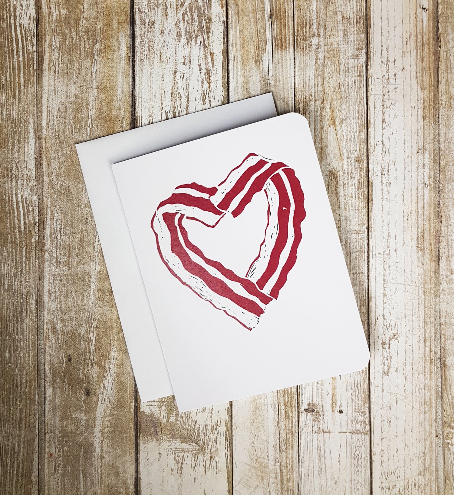 A photo of a white card. It has bacon strips in a heart shape.