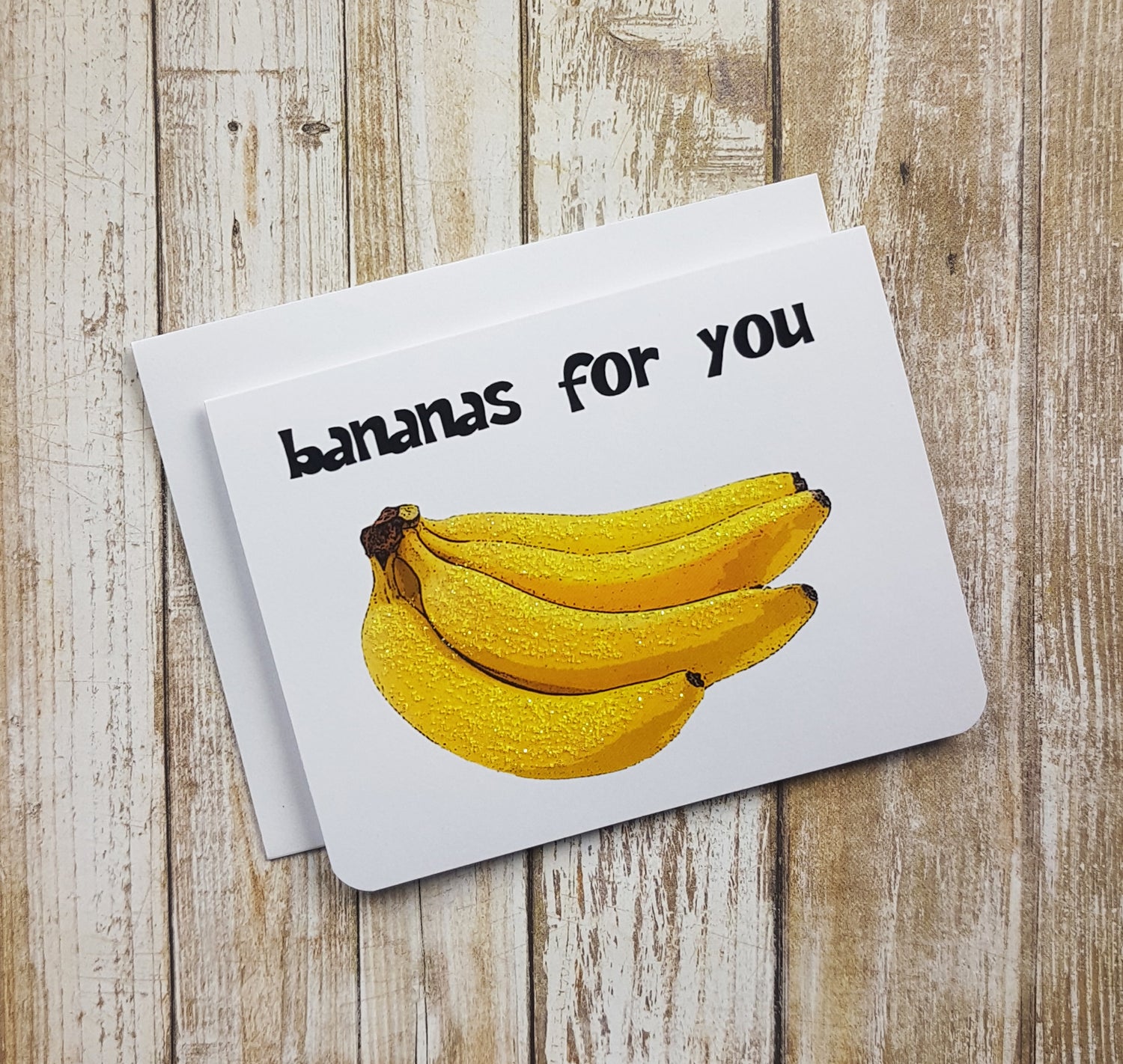 A photo of a white valentines card. It has an image of bananas on it. Text on card reads, 'bananas for you.'