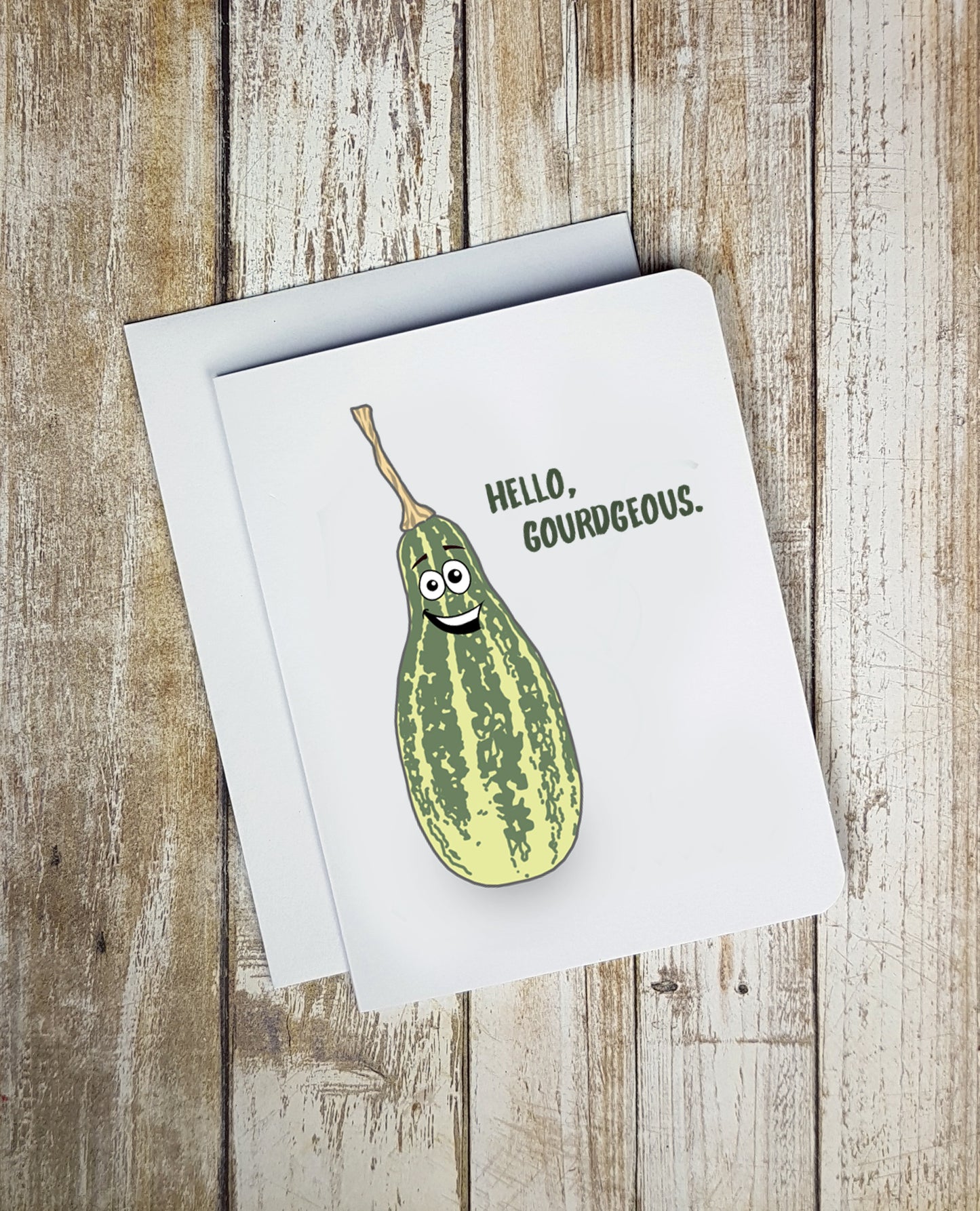 A photo of a white fun card. It has a smiling cartoon gourd on it. Text reads, 'Hello, Gorgeous.'