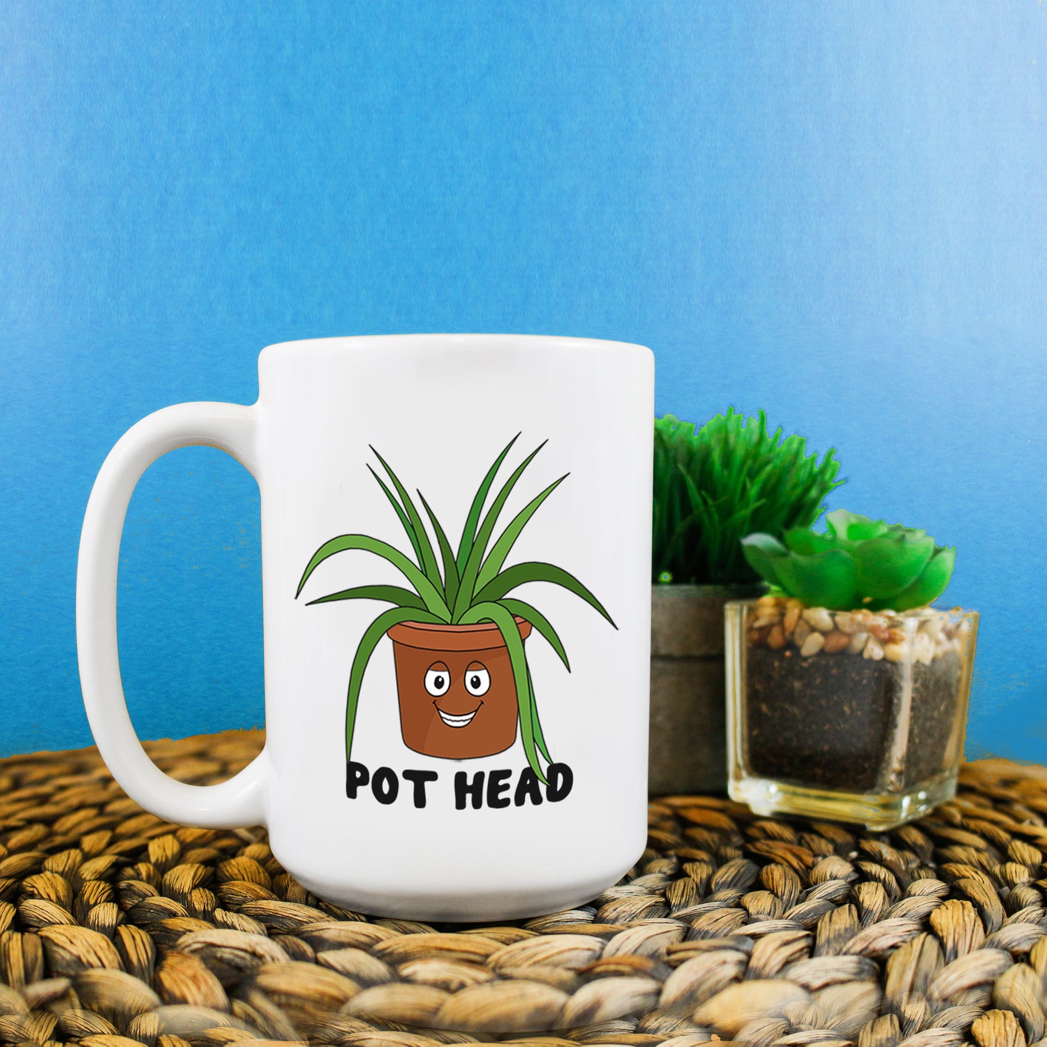 A funny mug. On the mug there's a smiling cartoon plant pot. Below it reads 'Pot Head.'