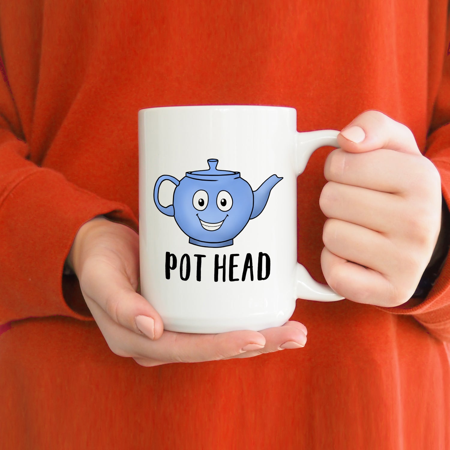 A photo of a funny coffee mug. It has a blue cartoon smiling tea pot on it. Text on mug reads 'Pot Head.'