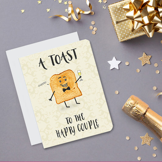 A fun wedding card. It has a piece of toast on it with a smiling face and stick arms and legs. It's holding a glass of champagne and a bowtie and saying, 'cheers.' Text on card reads, 'A Toad to the Happy Couple.'
