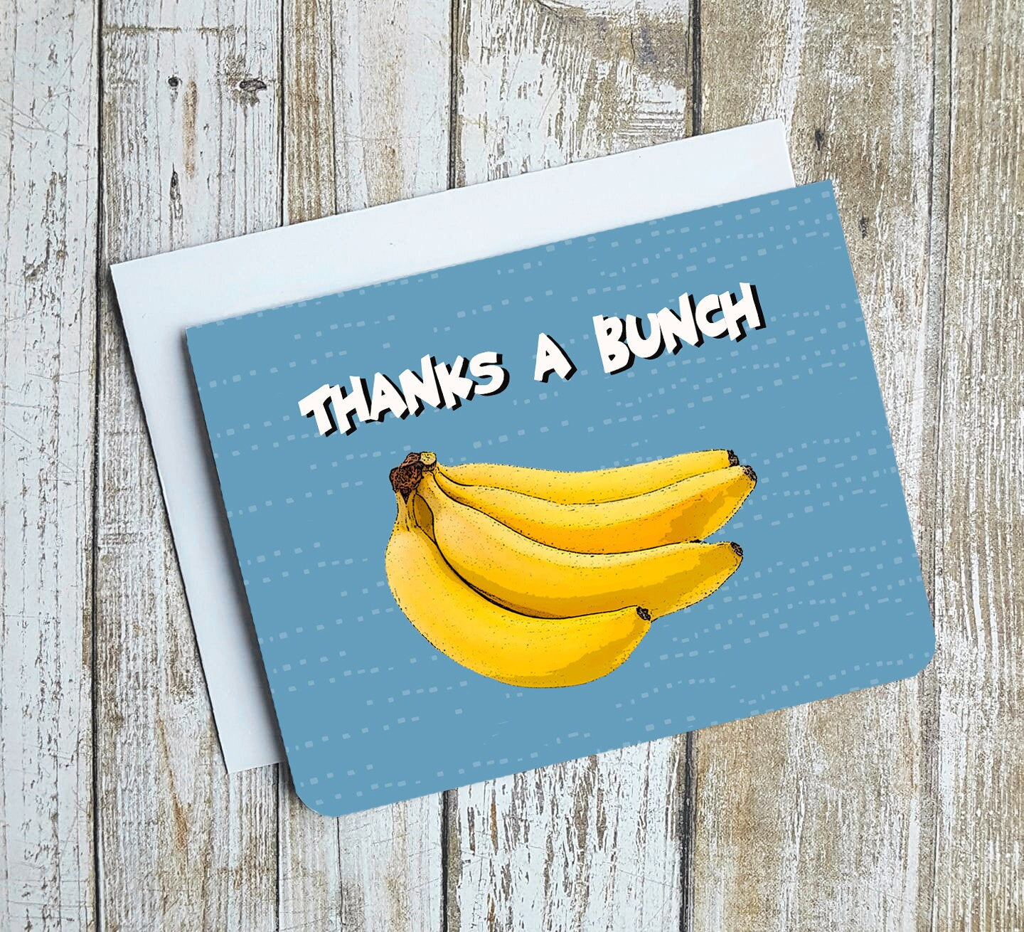 A photo of a blue thank you card. It has a bunch of cartoon bananas on it. Text on card reads, 'Thanks a Bunch.'