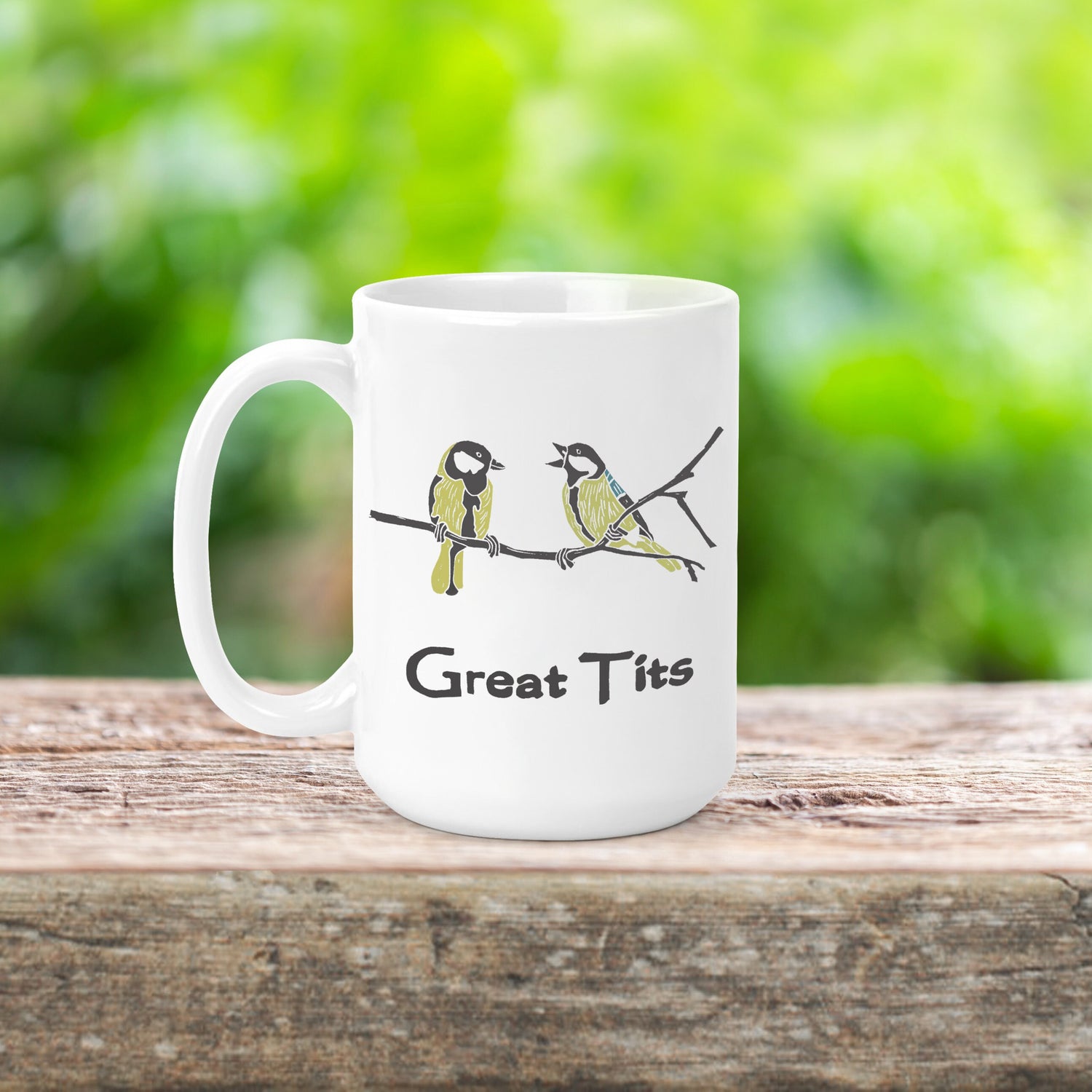 A photo of a funny mug. It's white and has a graphic of two blue tits on it. Text on mug reads, 'Great Tits.'