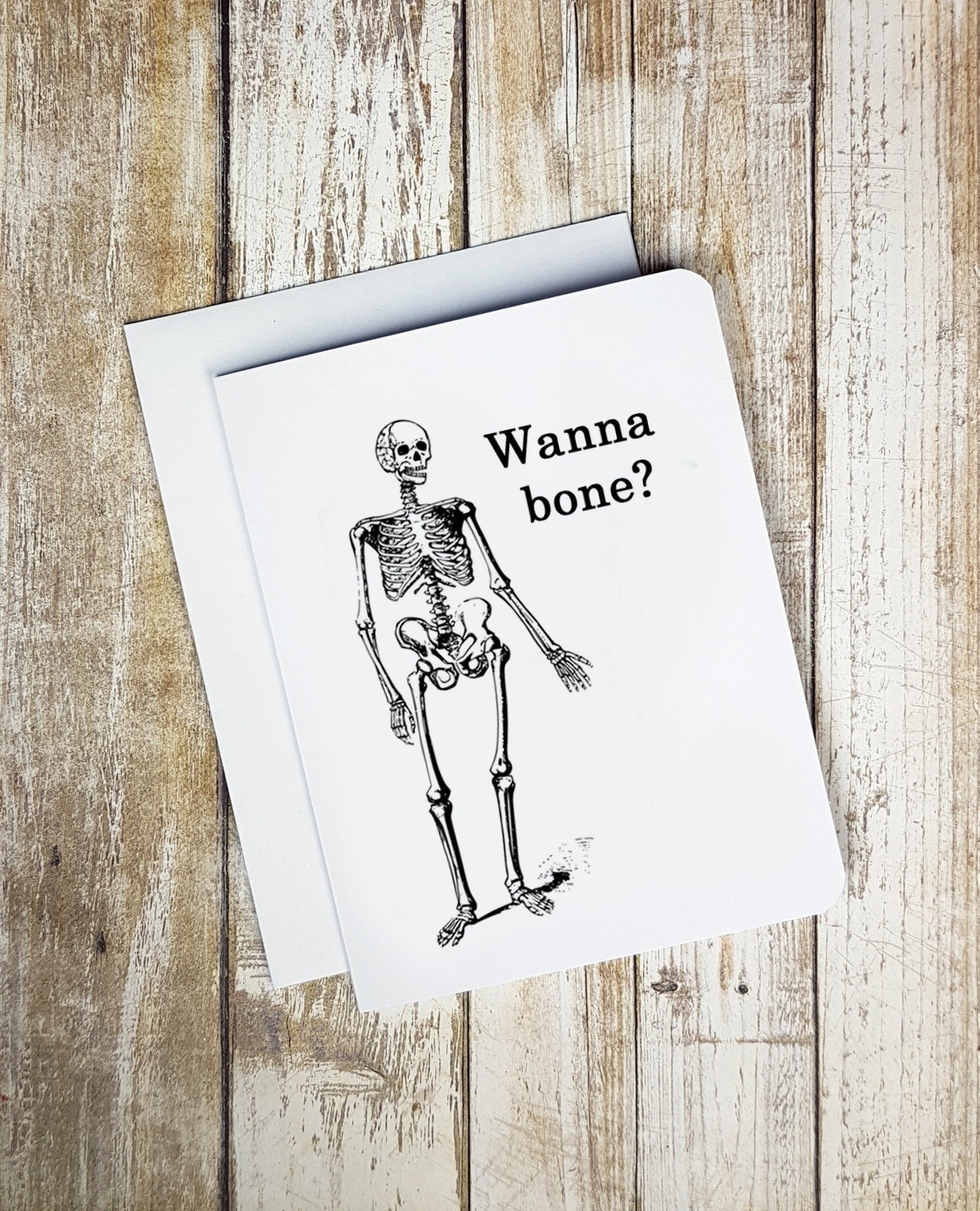 A funny Valentine's Day card. It has a cartoon skeleton on it. Text reads 'Wanna Bone?'