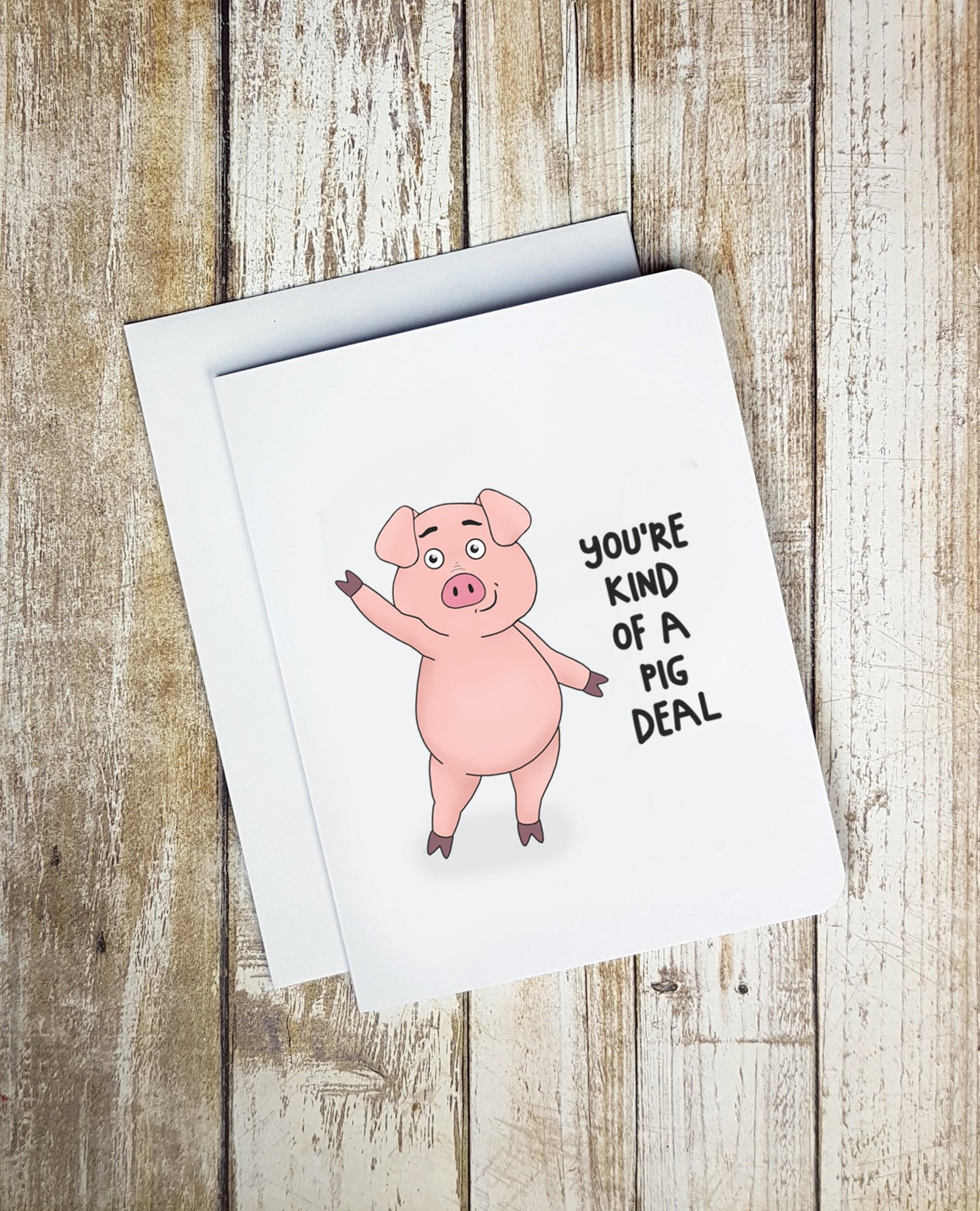 A photo of a white greeting cards. It has a waving cartoon pig on it. Text reads 'You're kind o a Pig deal.'
