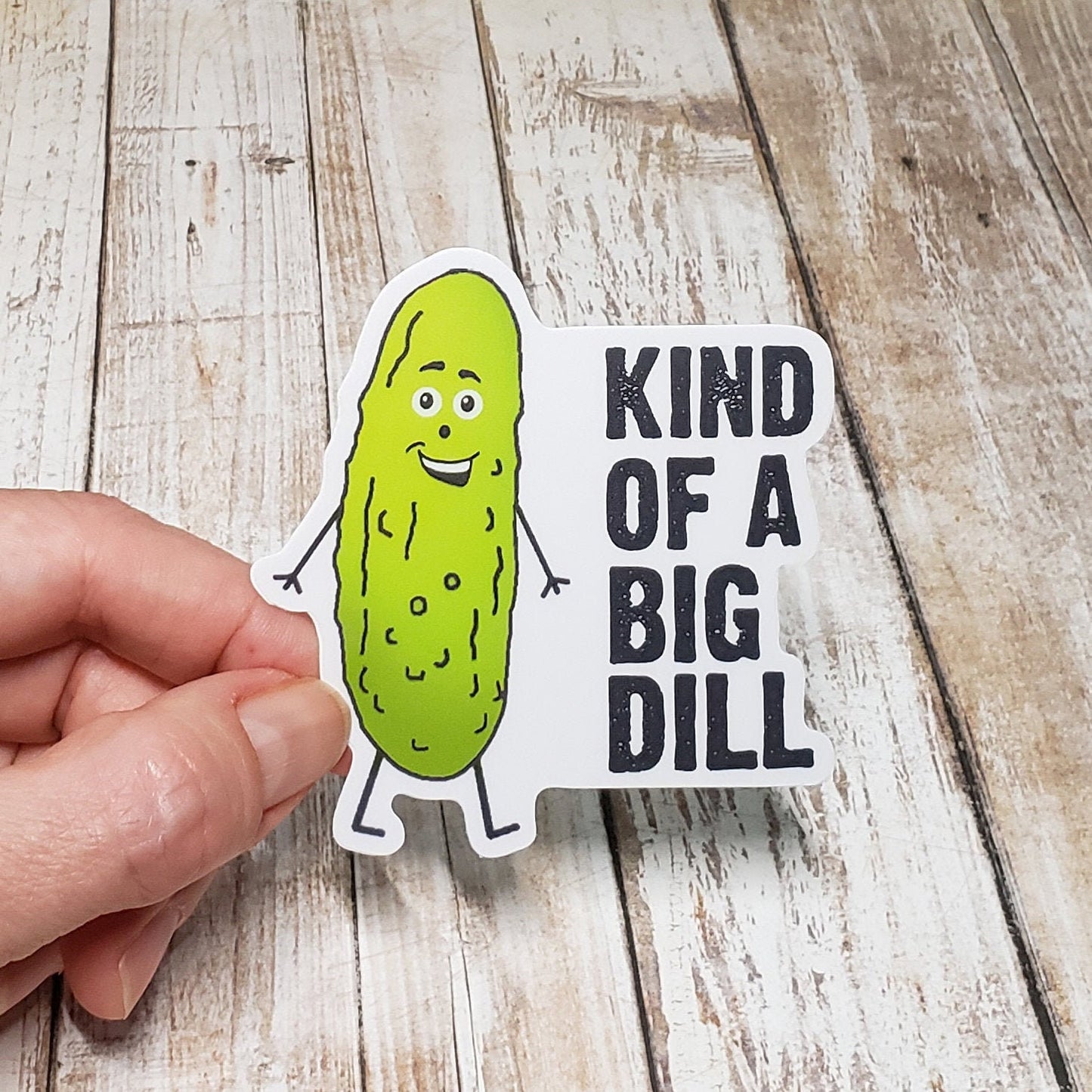 A photo of a cute sticker. It's of a cartoon pickle with a smiling face. Text on sticker reads 'Kind of a big dill.'