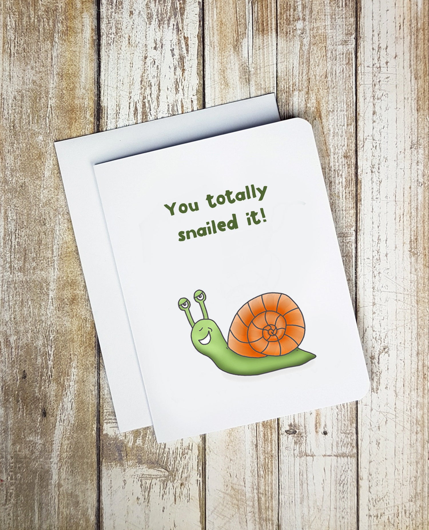 A photo of a greeting card. It has a smiling cartoon snail on it. Text reads, You Totally Snailed It!