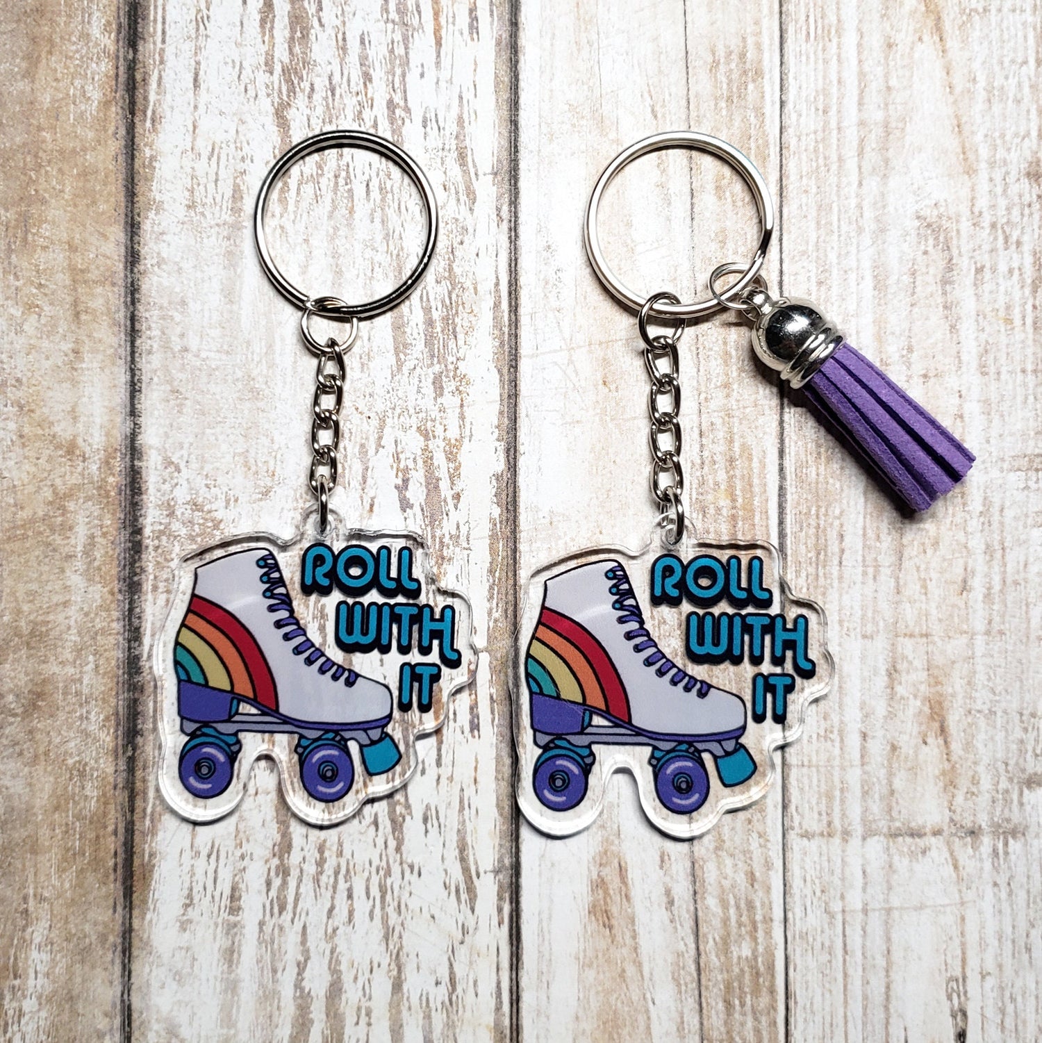 A photo of two acrylic keychains. The key chain is a retro colourful roller-skate. Text on keychain reads 'Roll With It.'